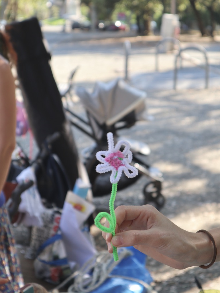 Fiore fatto con materiali di scarto pieghevoli. Colori: rosa, verde, bianco.